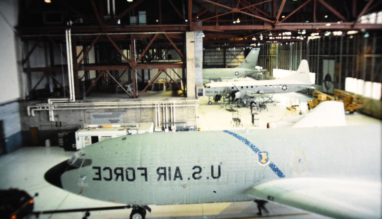 three aircraft in a large hanger being maintained