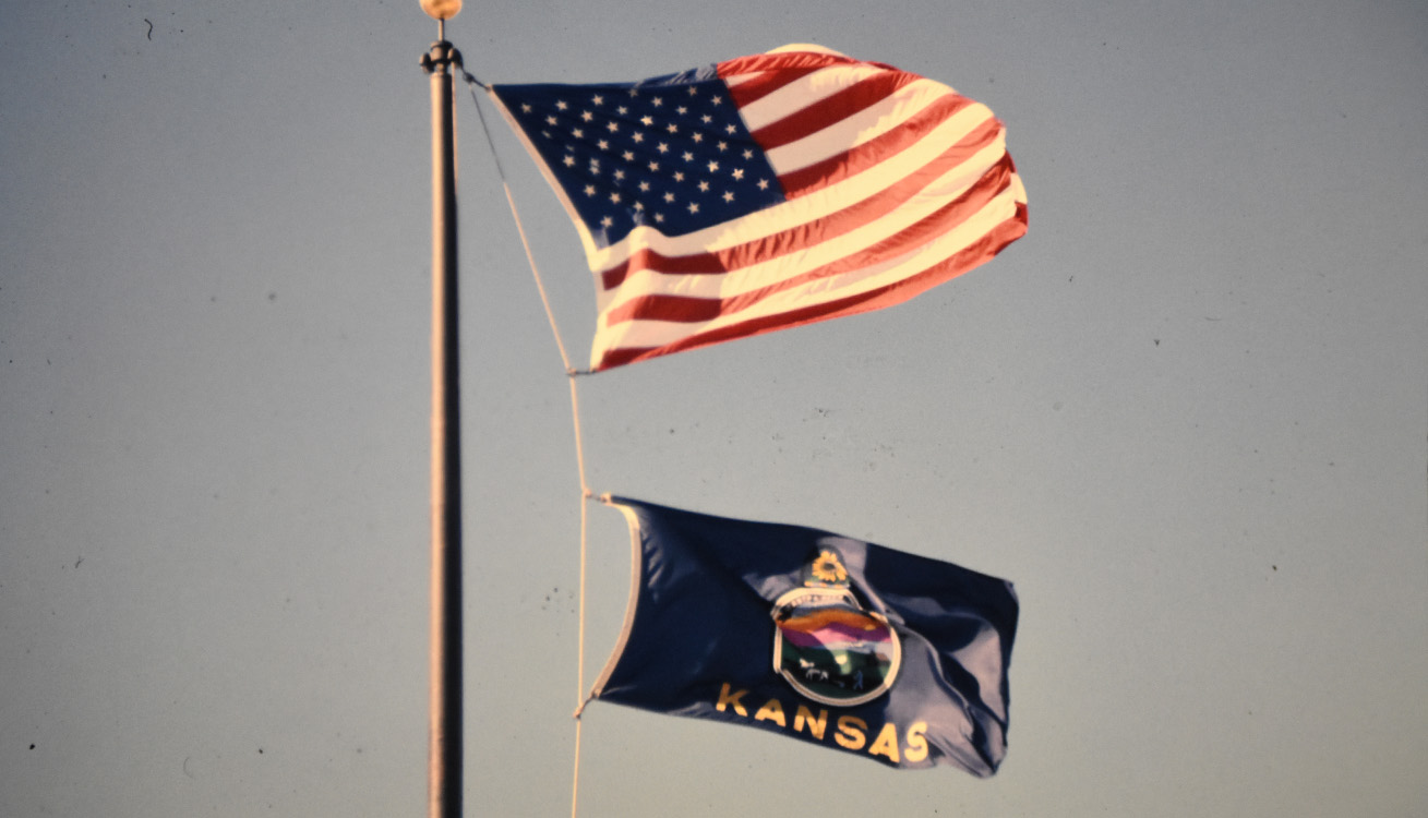 close up of a flag pole with the US Flag flown on the top and the Kansas flag is below it