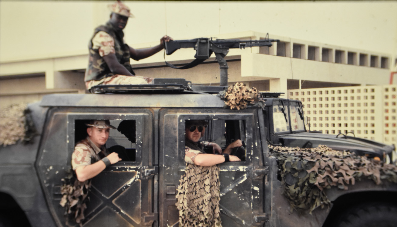 four service members riding on a humvee