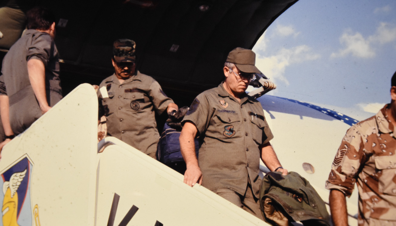 close up picture of four service members departing a plane