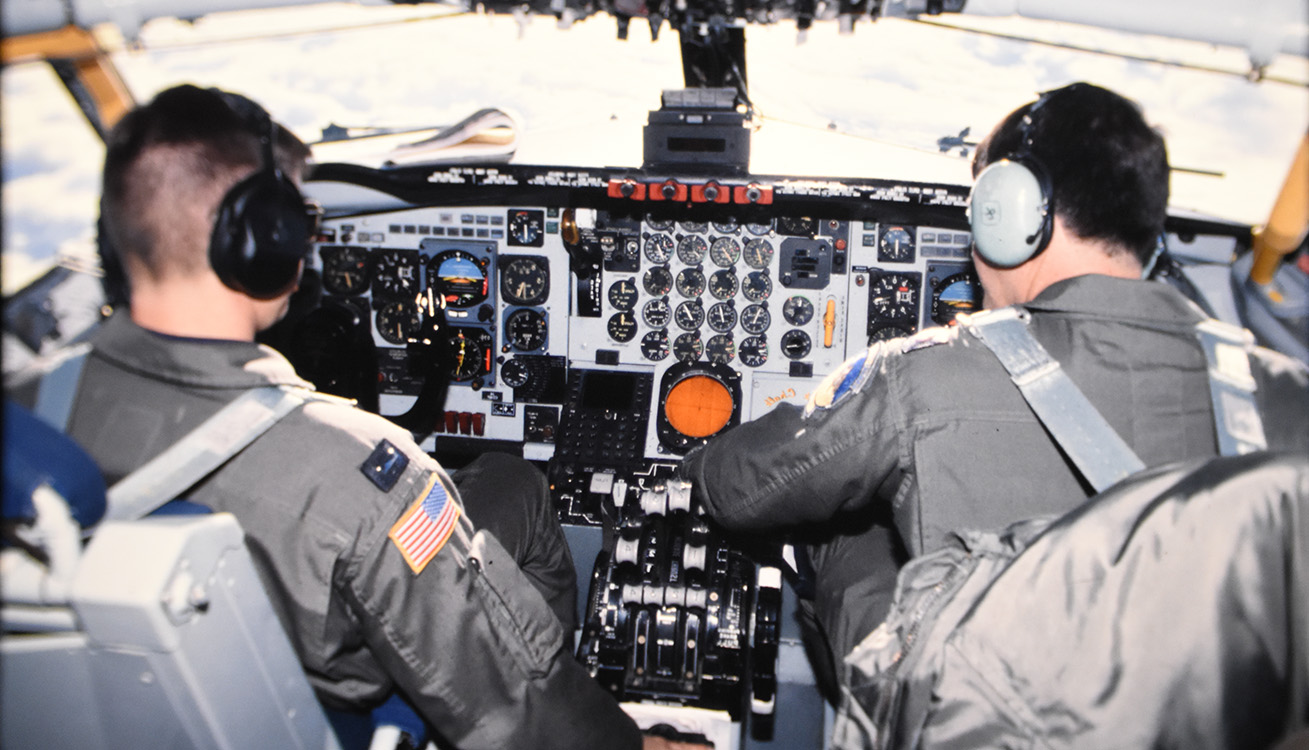 looking over the shoulders of two pilots inside a cockpit of KC-135 aircraft