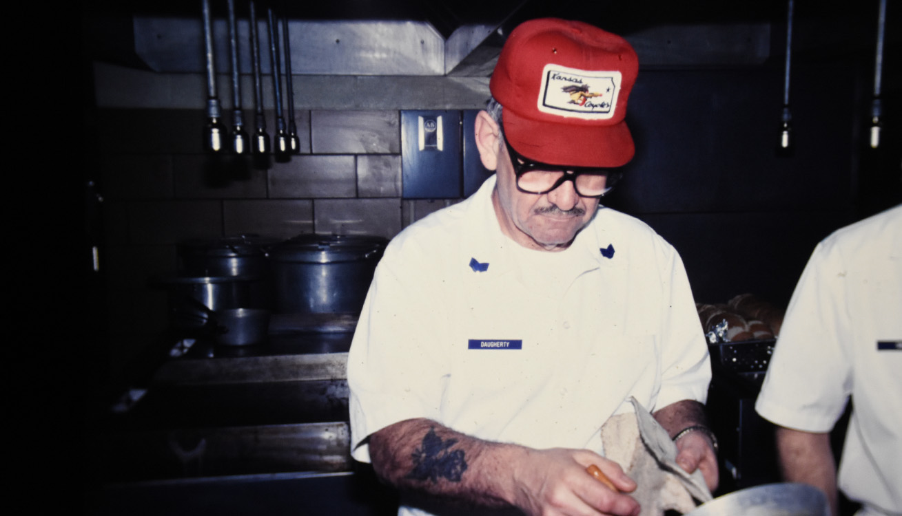 military member in white services uniform preps for meals